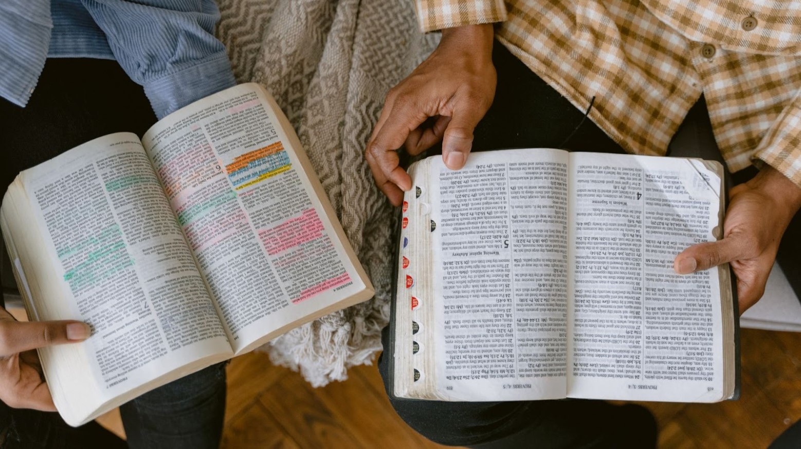 Two people work together while reading their Bibles and highlighting important passages