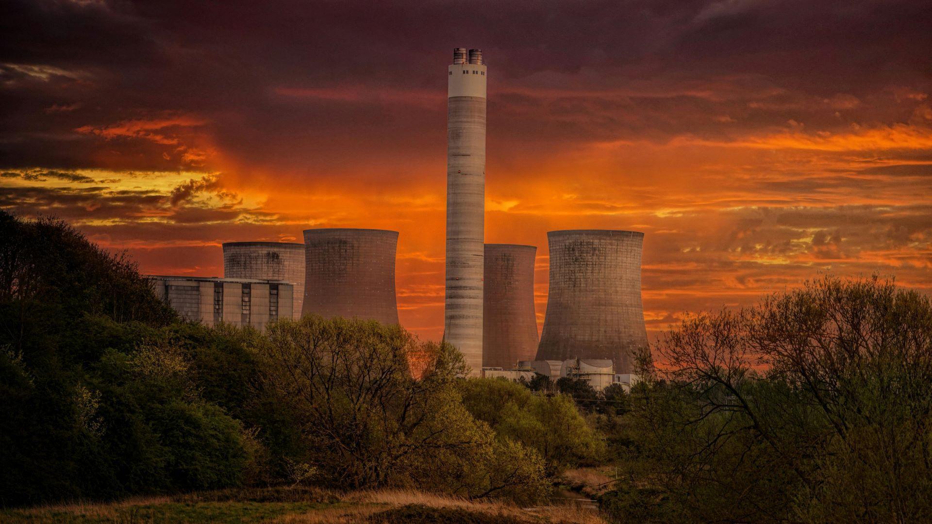 A shot of a nuclear power plant with a dynamic orange sky behind it.