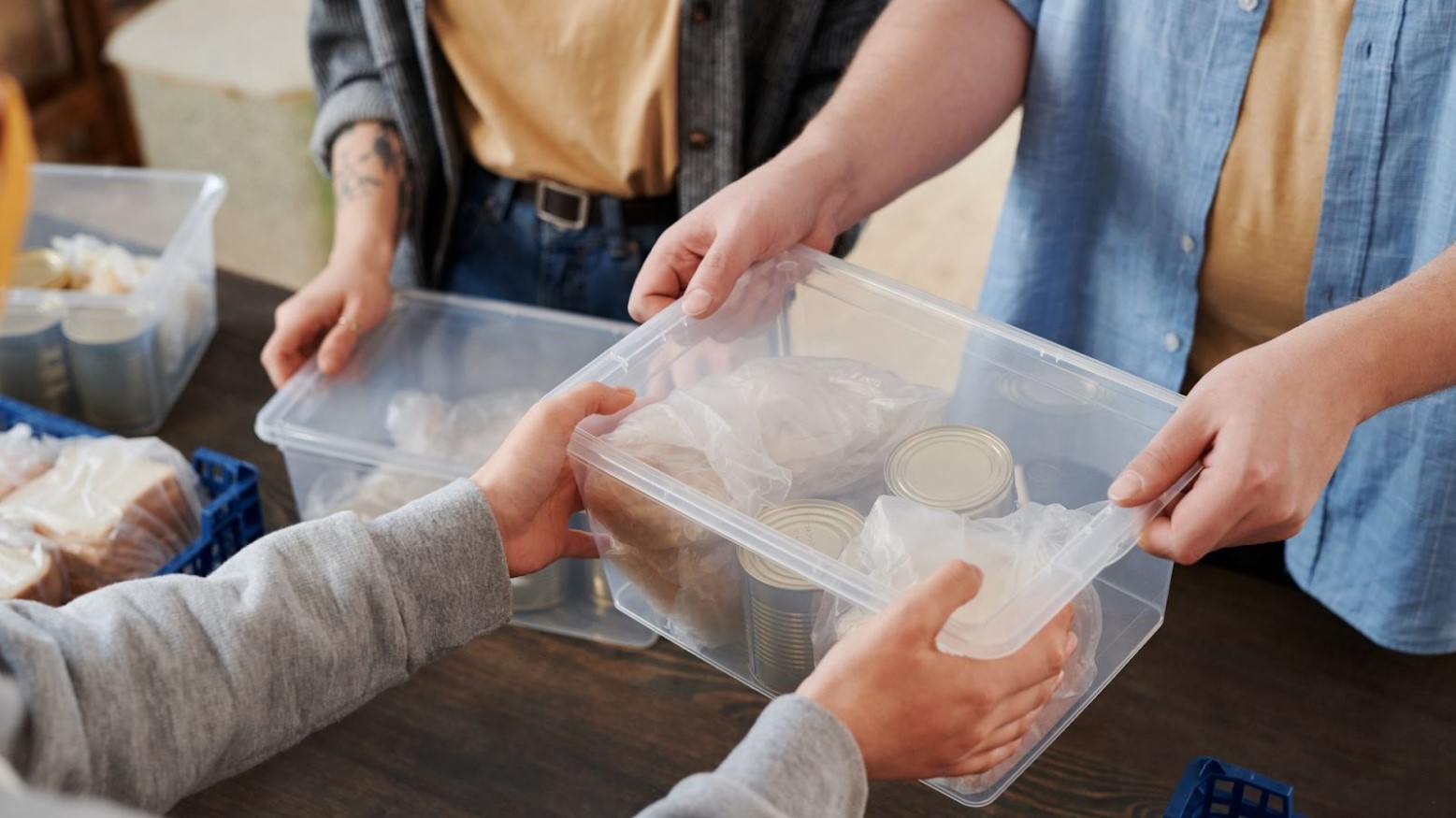 One person is hanging a man a clear box with food inside at a food bank