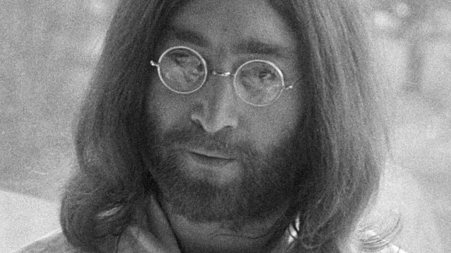 A black and white photo of John Lennon wearing glasses.