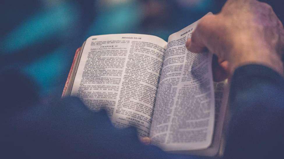 A man holding the Bible and turning a page of it.