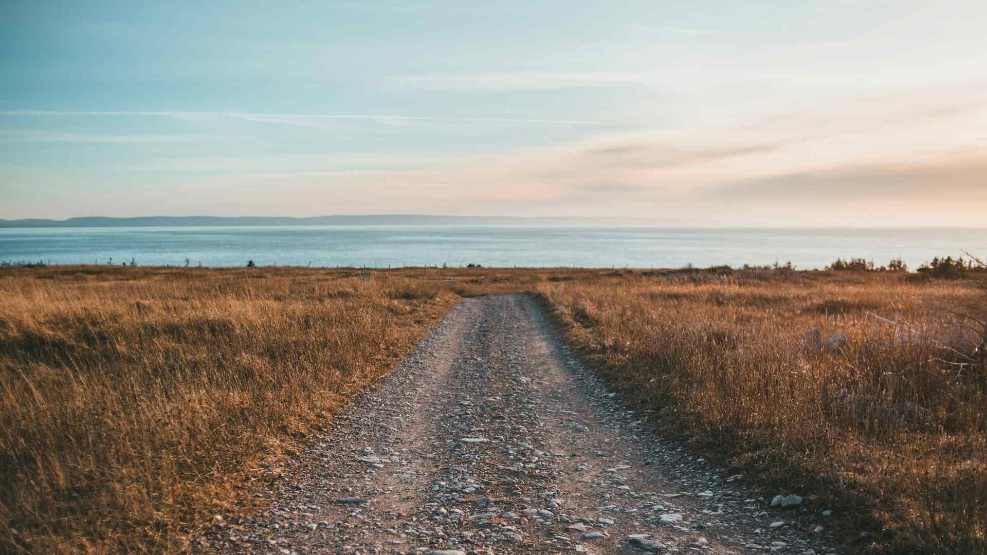 An empty dirt road overlooking a coastline.