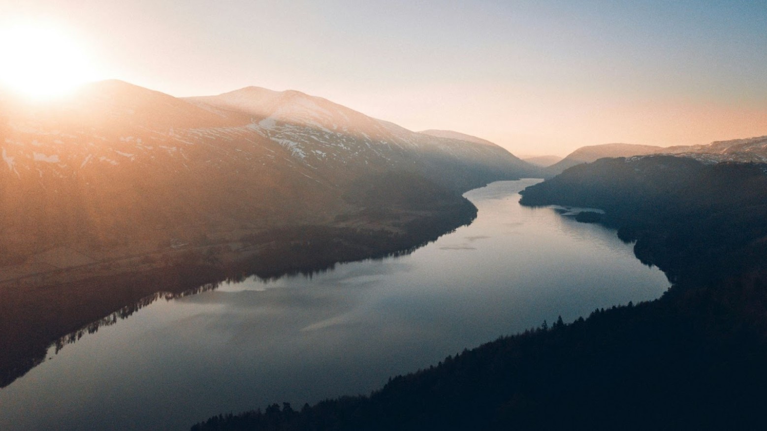 An aerial view of a large river in the United Kingdom during sunrise.