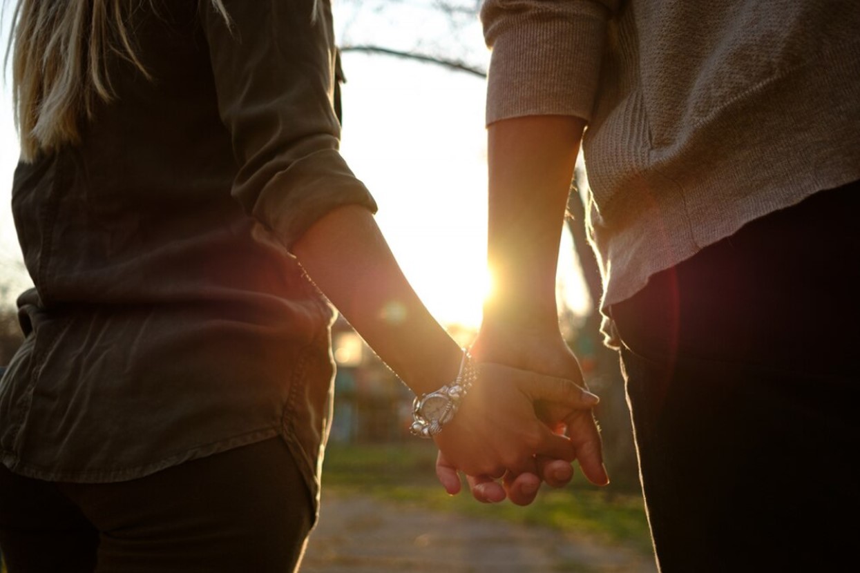A couple is holding hands while the sun sets