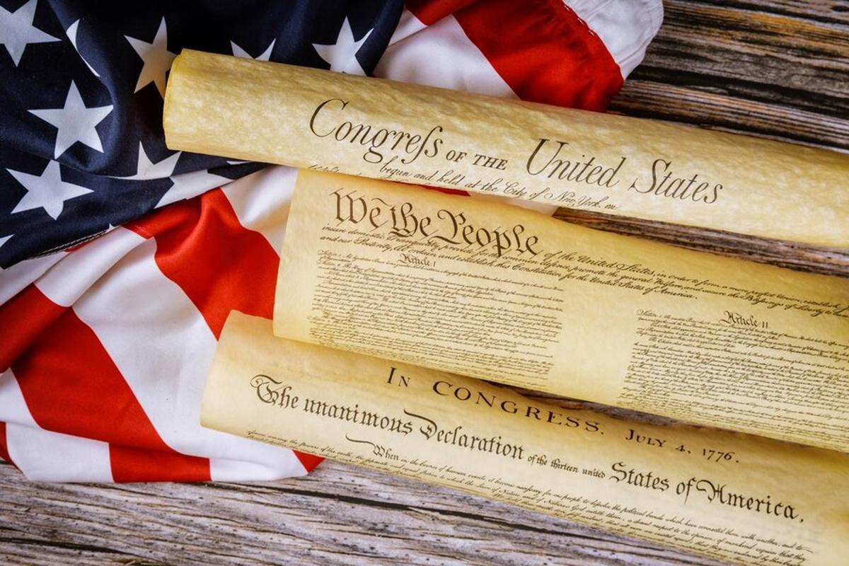 Photograph of the US Constitution rolled up atop an American flag