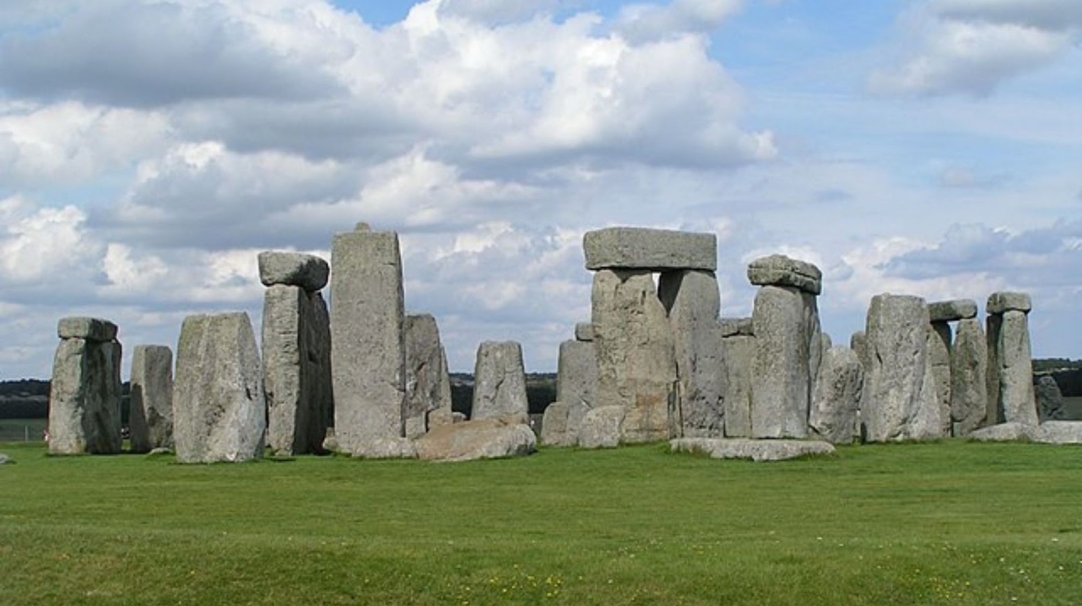 Stonehenge on a sunny day. The stones are all in one circle, with some stones on top of each other.