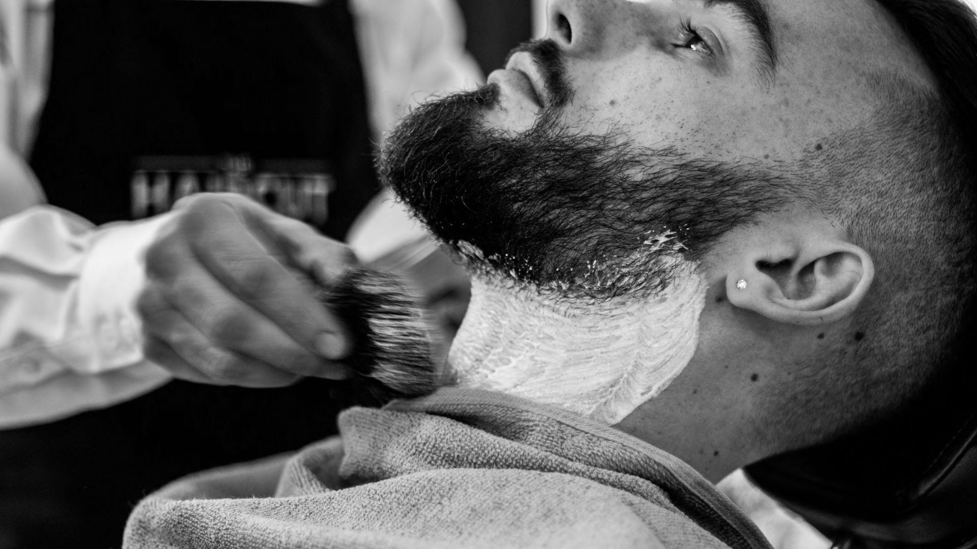 A man getting his beard shaved by a barber.