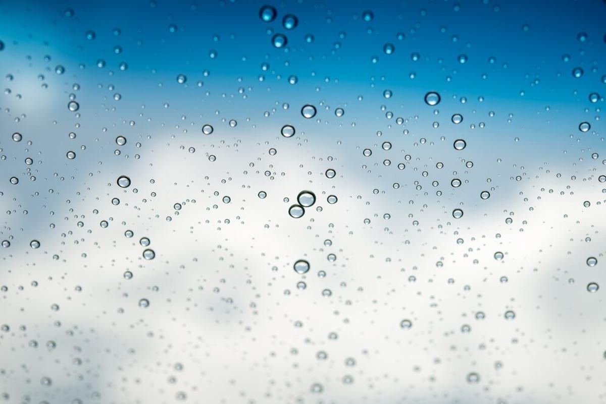 Water droplets in front of a blurry photograph of a cloud
