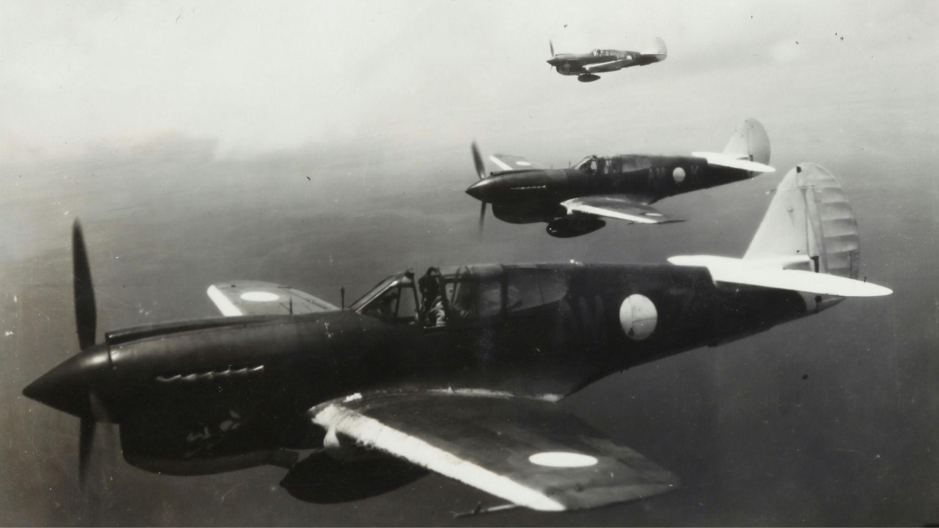 A black and white photo of three fighter planes seen in the sky in World War II.