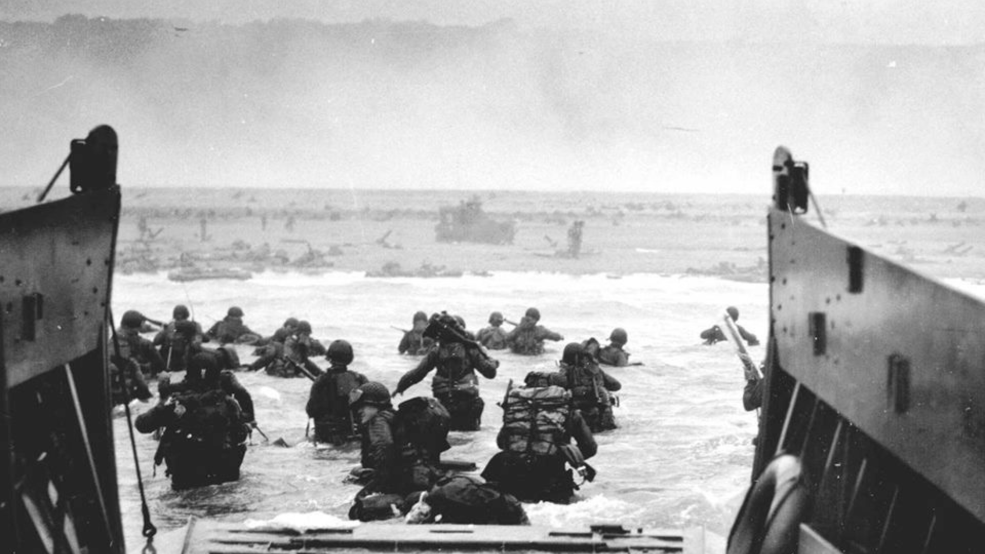 Black-and-white photo of U.S. Soldiers disembarking a landing craft at Normandy, France, June 6, 1944.