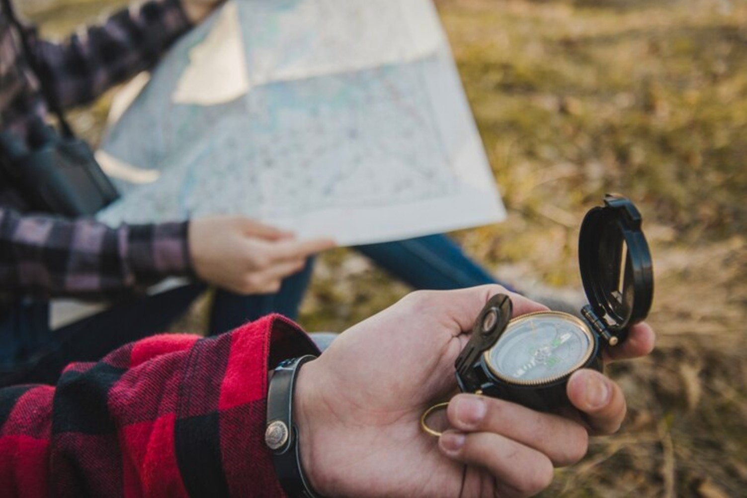 A man in a shirt is pictured holding a compass alongside his partner