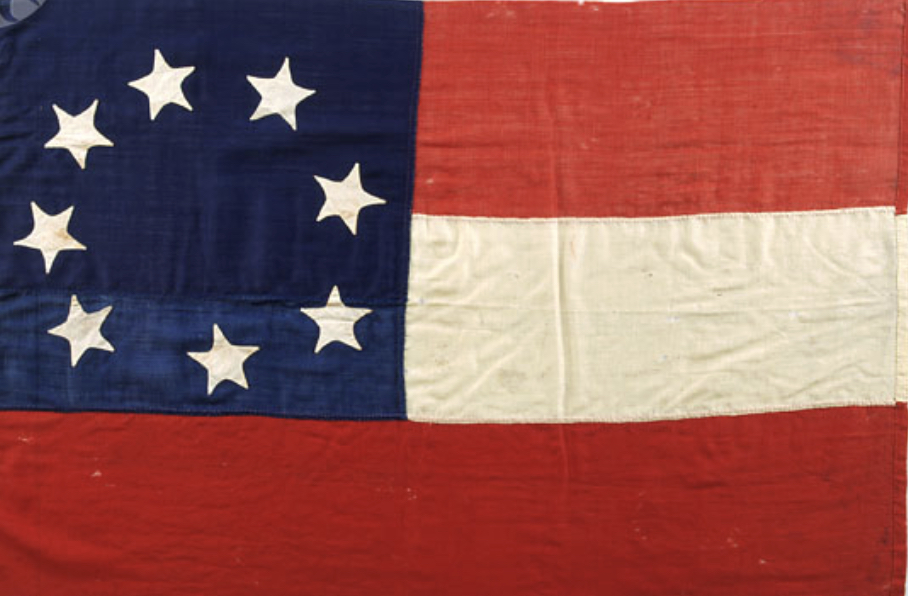 A vintage flag with 13 stars, two red stripes, and one white stripe