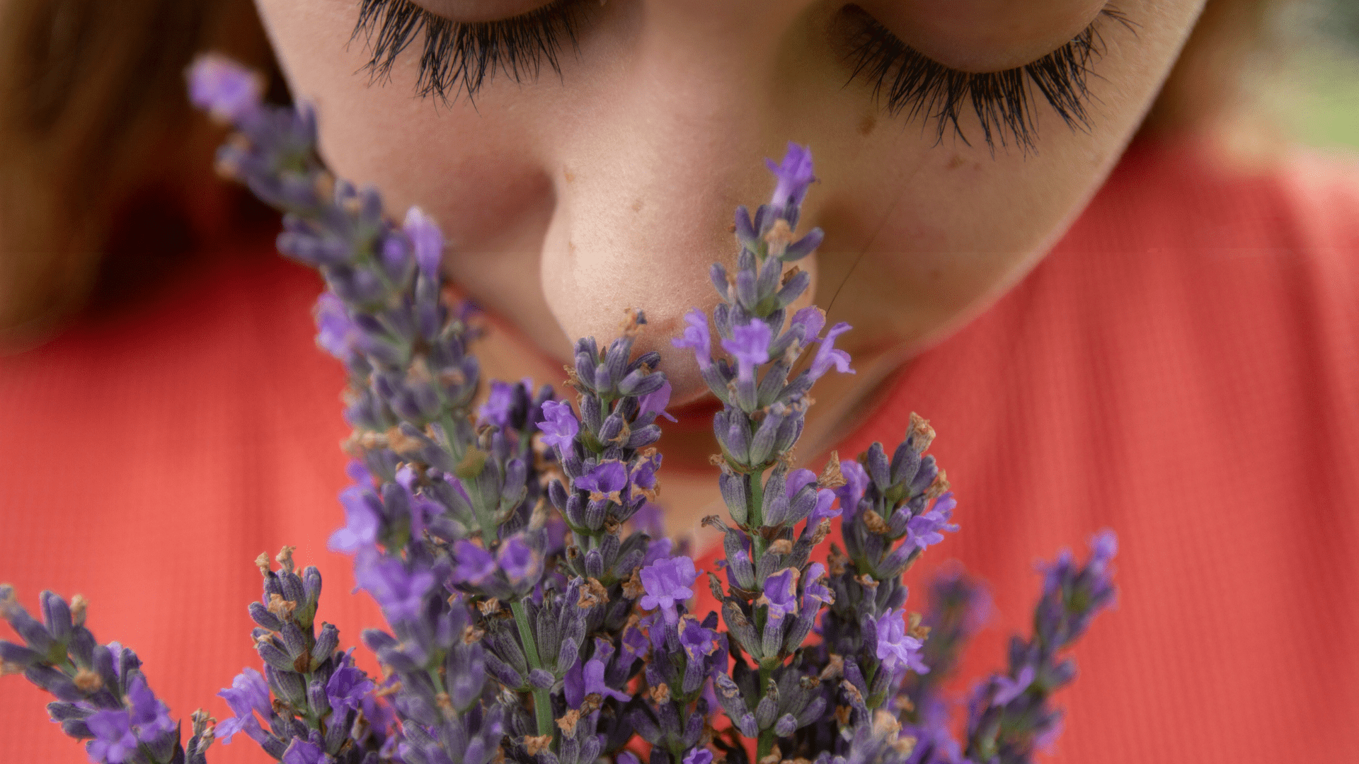 A girl smells lavender with her eyes closed.