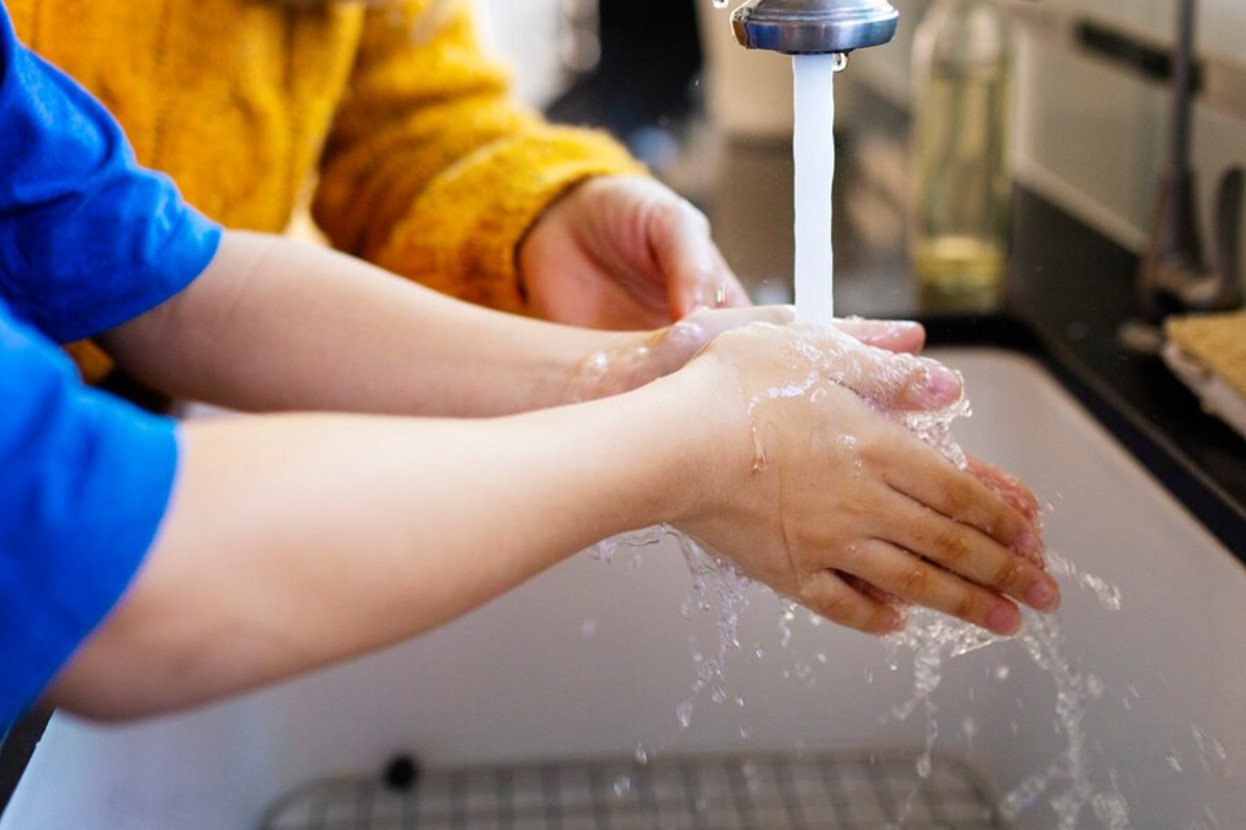 Kids washing their hands in the kitchen sink