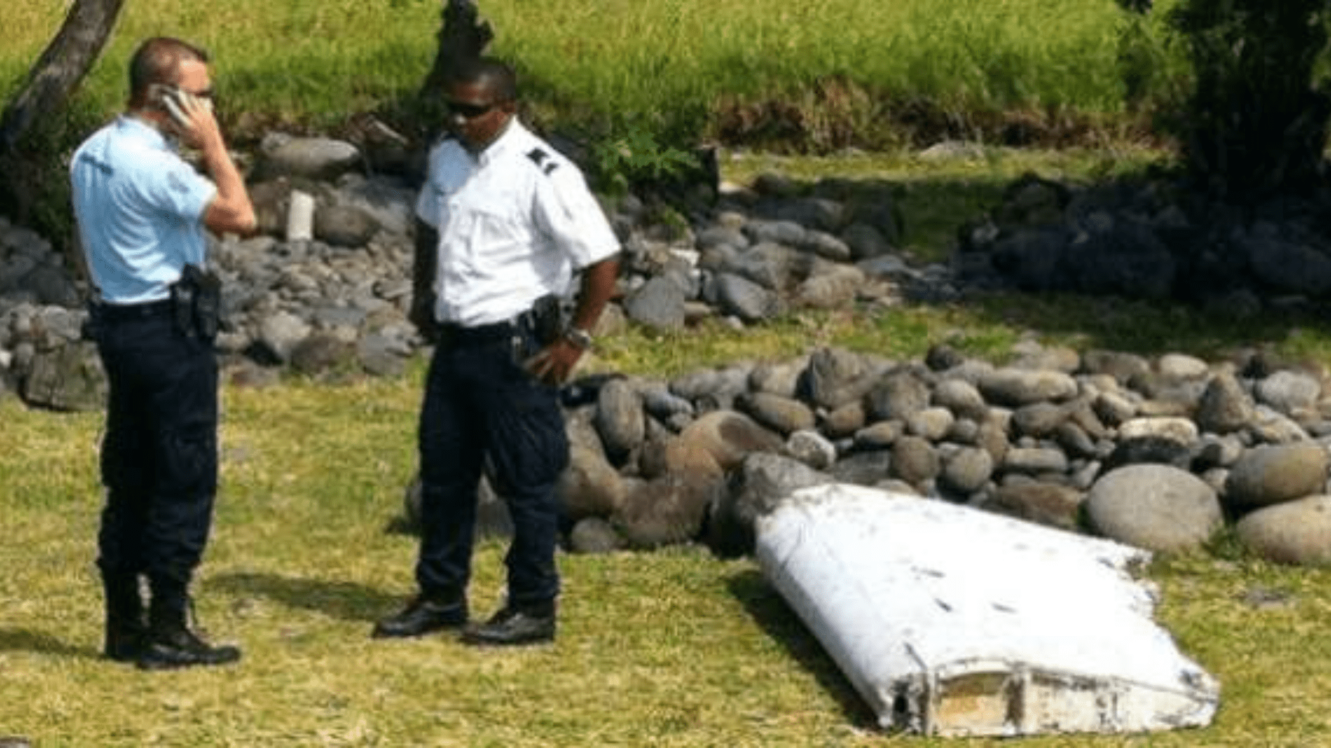 Two men stand near the MH370’s flaperon on Reunion Island.