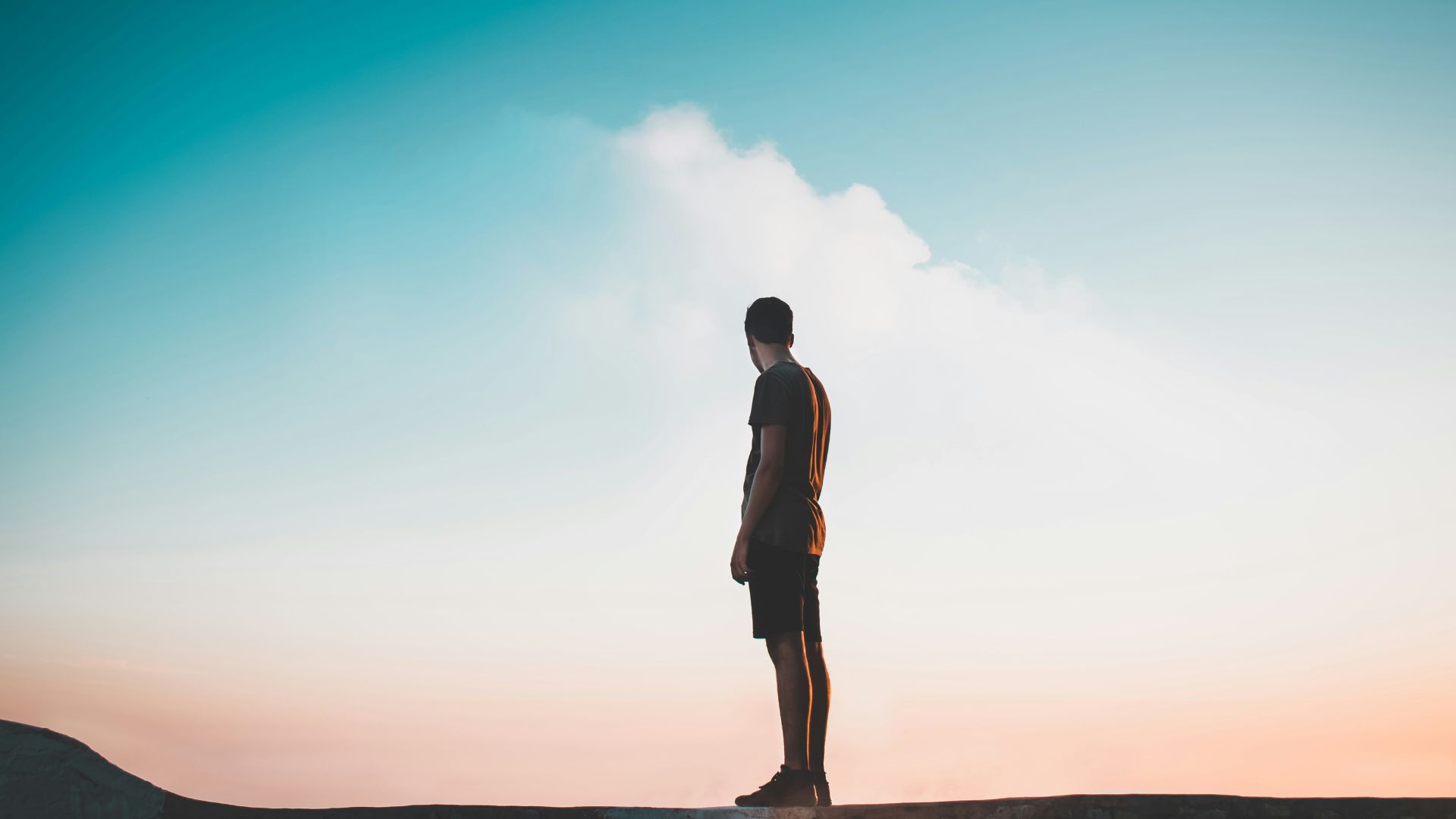 A man standing in front of a cloudy blue sky.