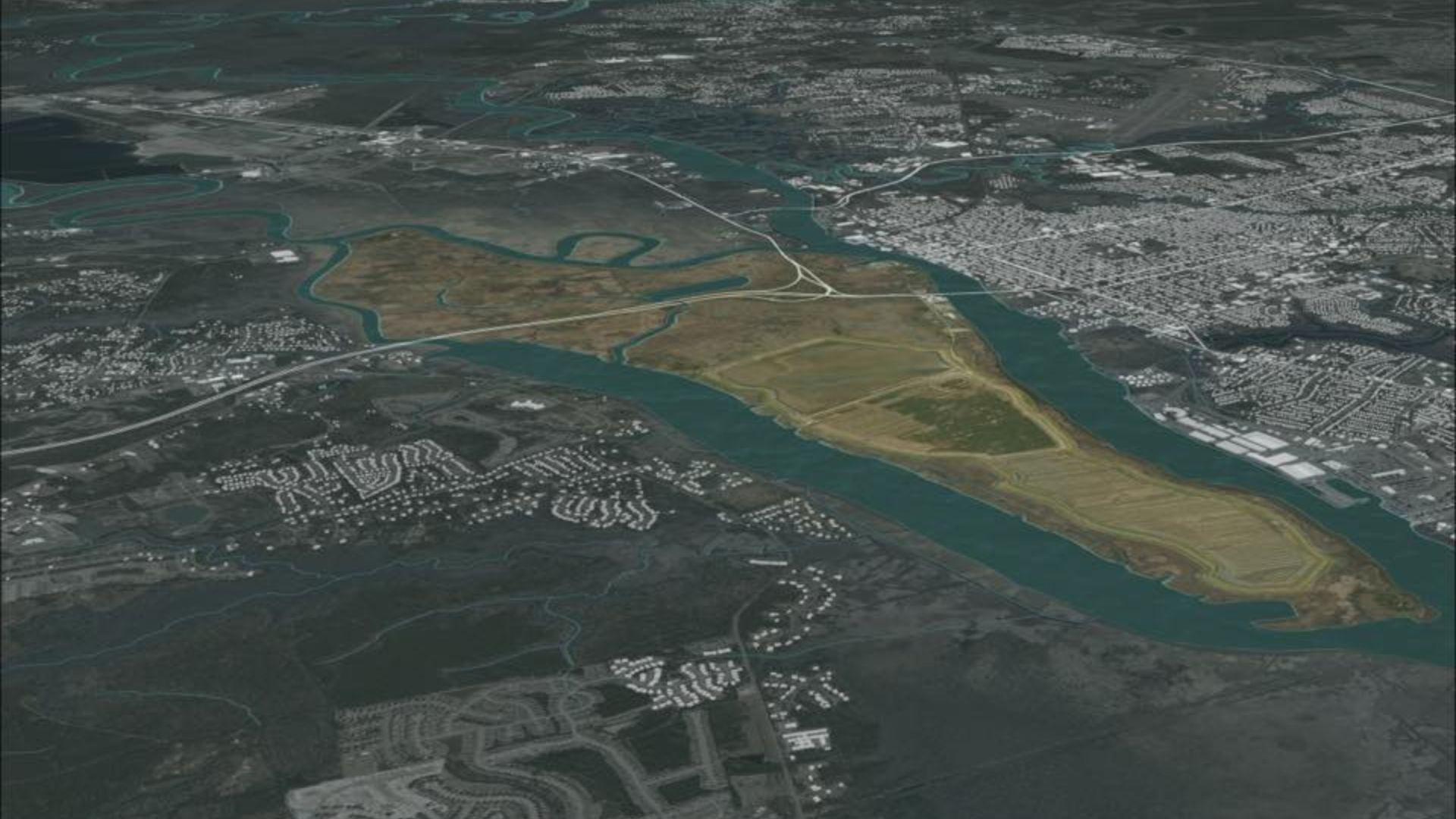 An aerial image showing a wide river snaking through a densely populated urban landscape. Residential and commercial areas are visible on both sides of the river, with roadways and green spaces interspersed among the buildings