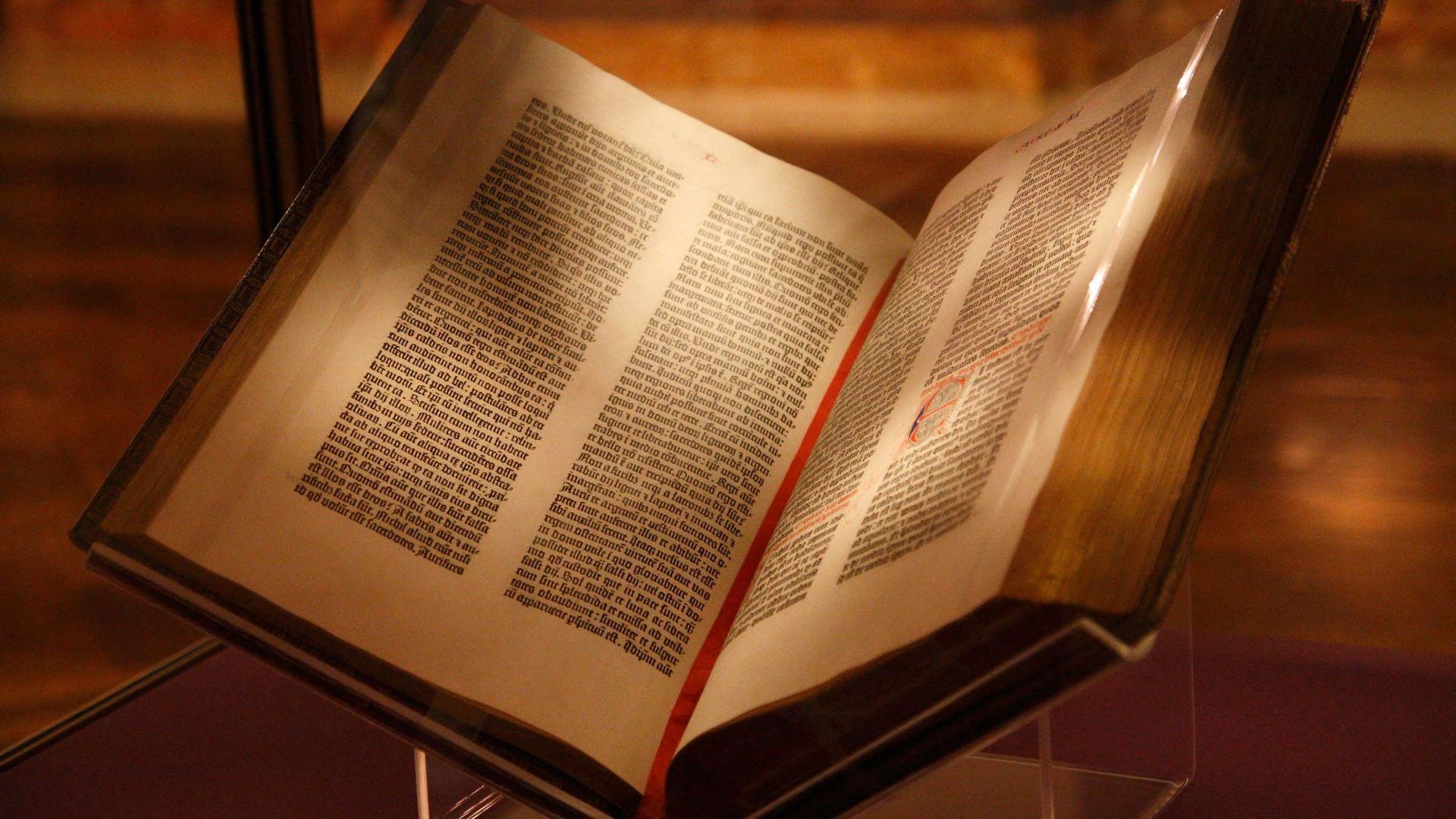 The Gutenberg Bible open with a red bookmarking in dim lighting.