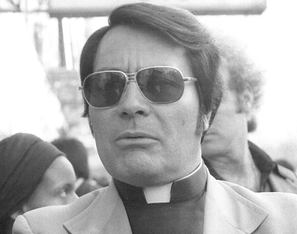 Image of JIm Jones pictured in a suit jacket and sunglasses