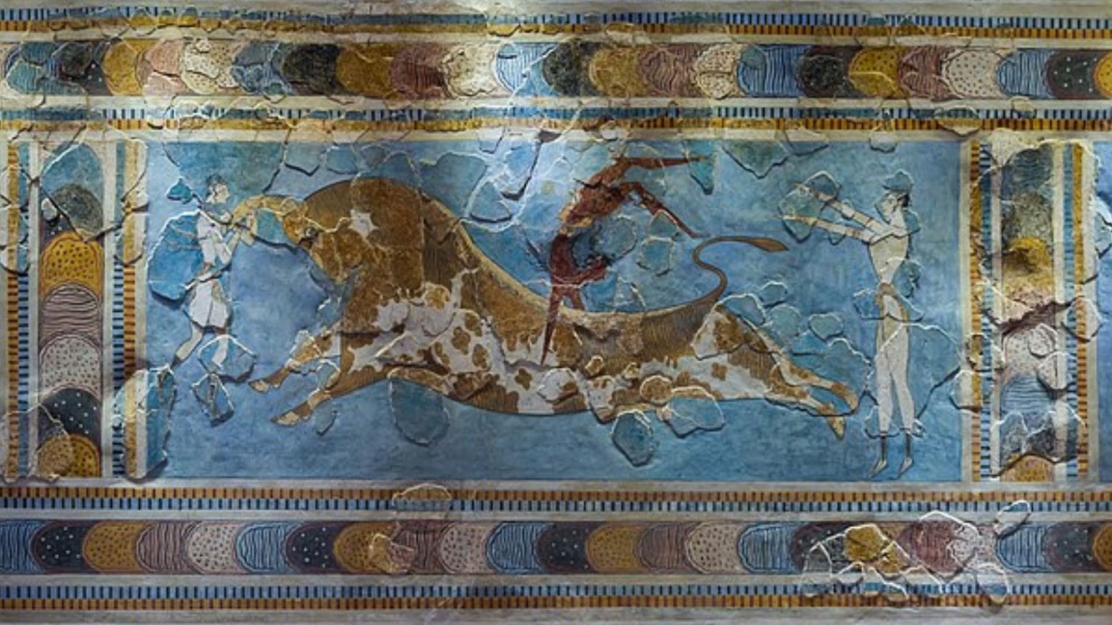 The Bull-Leaping Fresco painting. The painting shows a bull, with one man standing by his tail and another man standing by his head. Another man is in red and is jumping over the bull. Title: Bull-Leaping Minoan Fresco