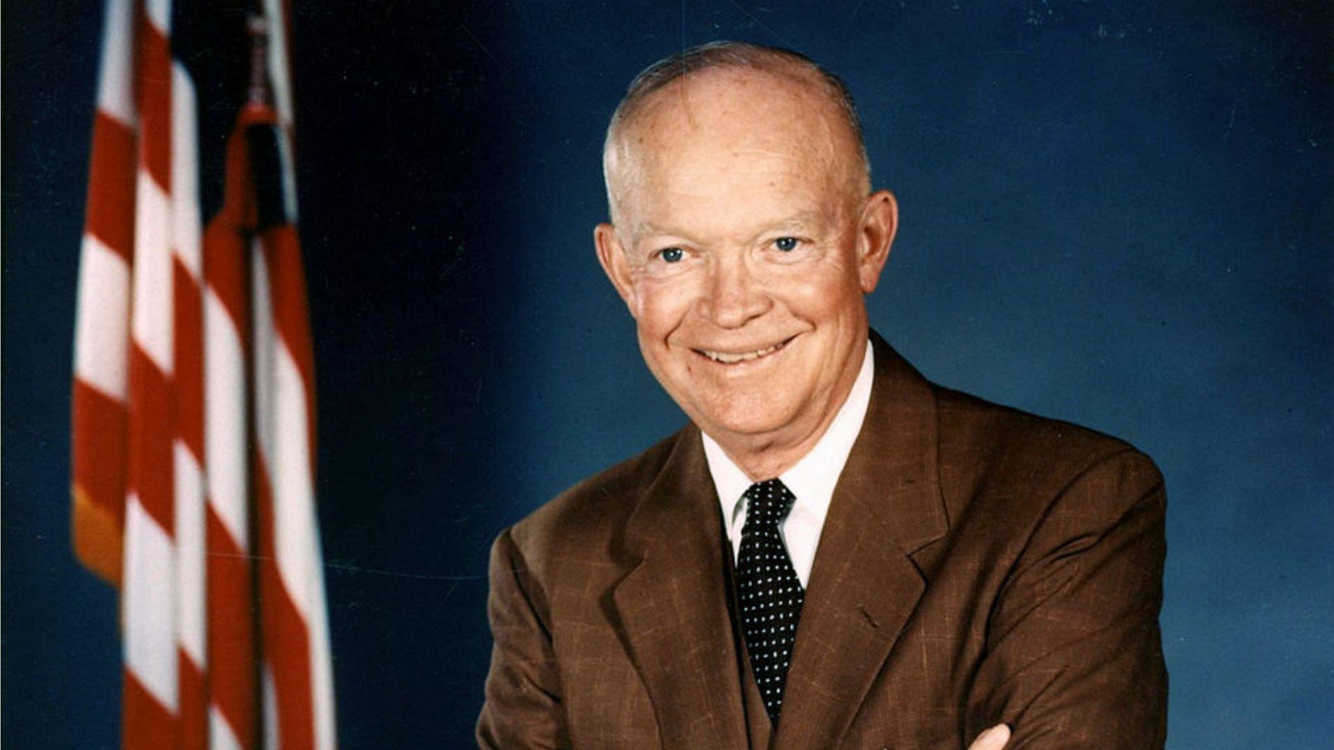 A formal portrait of former President Dwight D. Eisenhower, smiling in front of an American flag