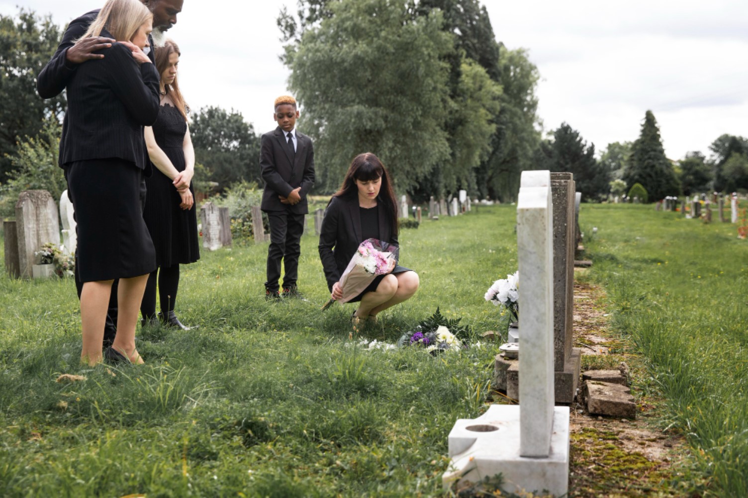 A family is pictured laying flowers at a cemetery