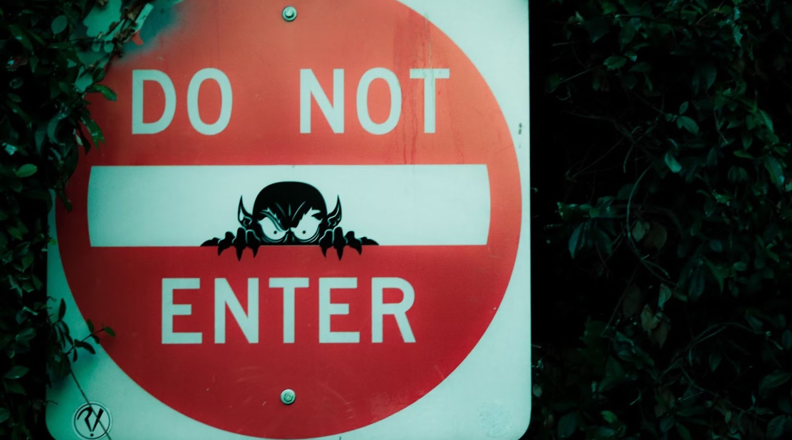 A white sign with a red circle that says “DO NOT ENTER” in white writing. There is a straight white line in the middle of a circle with a black figure inside.