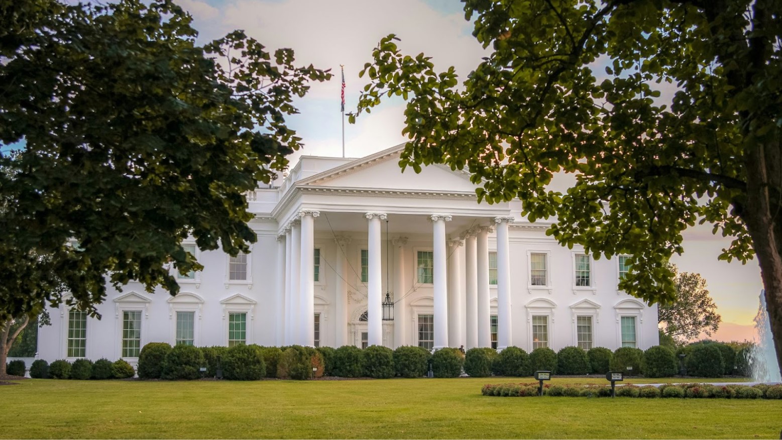 The White House seen in the daytime in front of a green lawn.