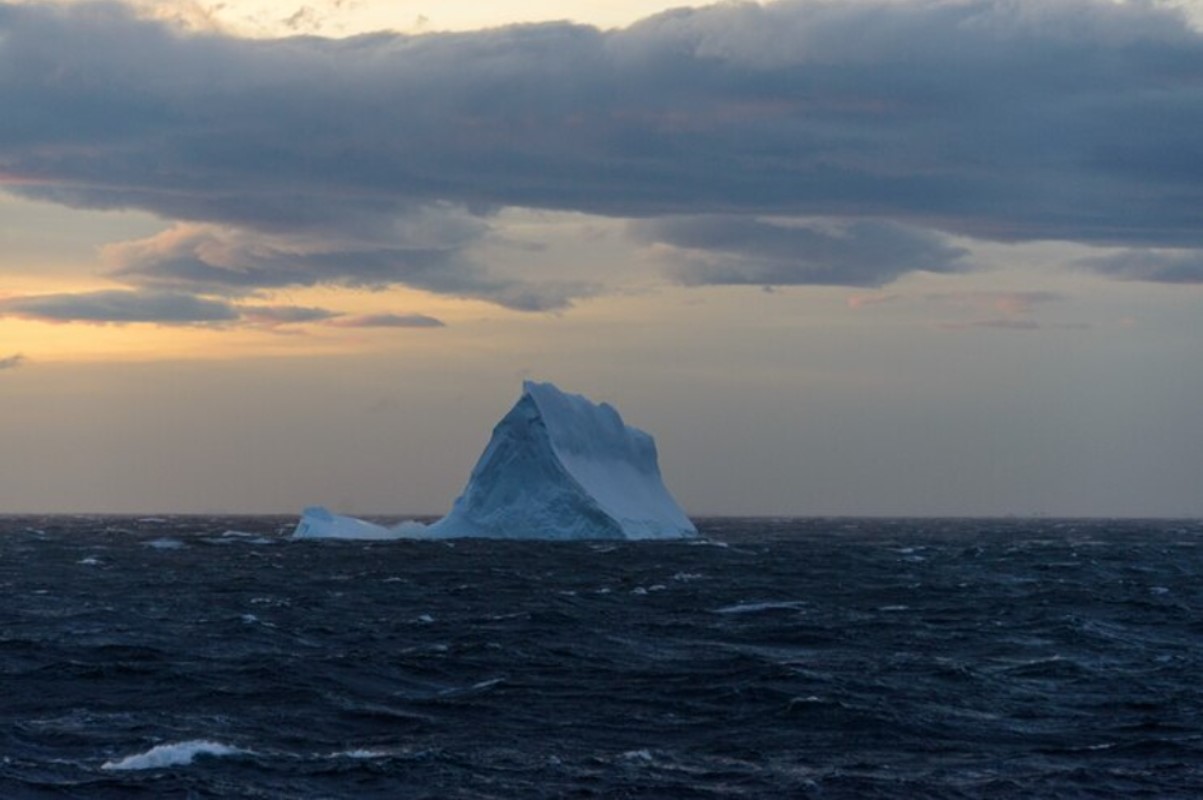An image of a large iceberg above the waves in the ocean