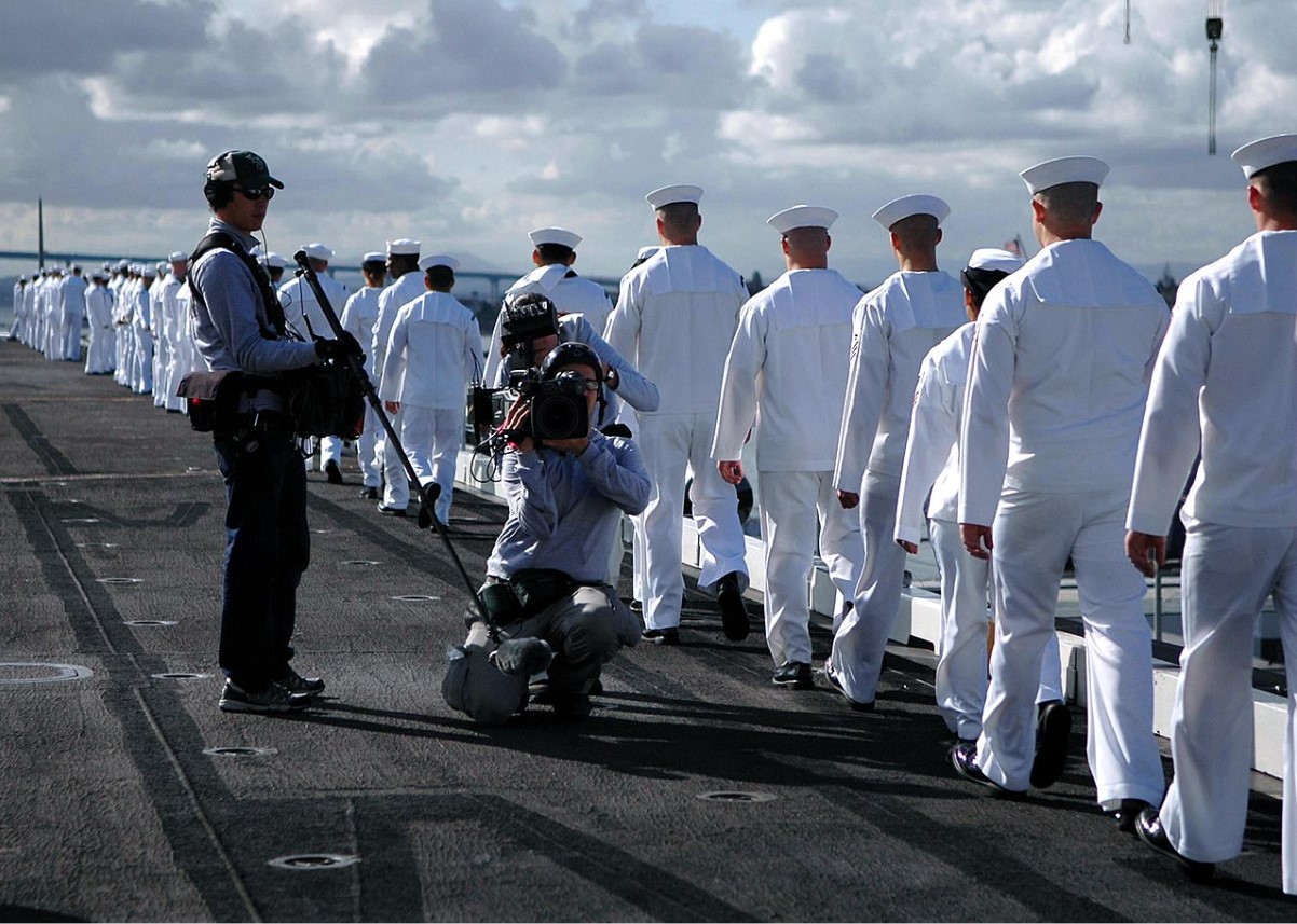 An image of several US Navy sailors walking down one side of the ship