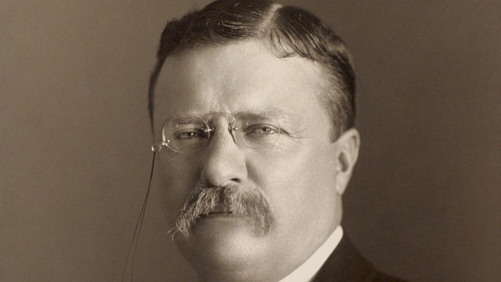 A sepia-toned photograph of Theodore Roosevelt, the 26th President of the United States, facing forward