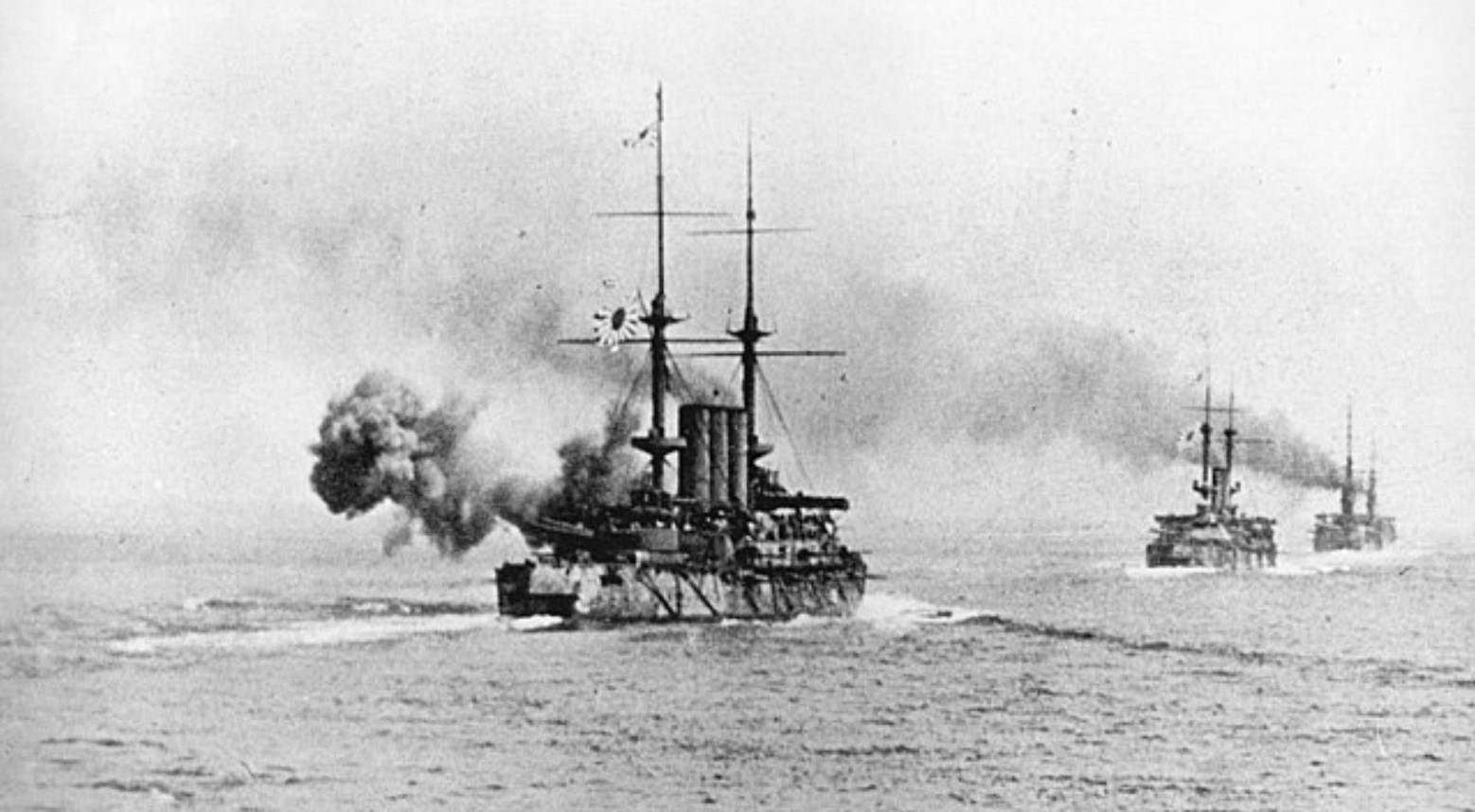 This is a black-and-white image from the Russo-Japanese War. It is from the Battle of the Yellow Sea, and it shows three ships in the sea. One of the ships is on fire.