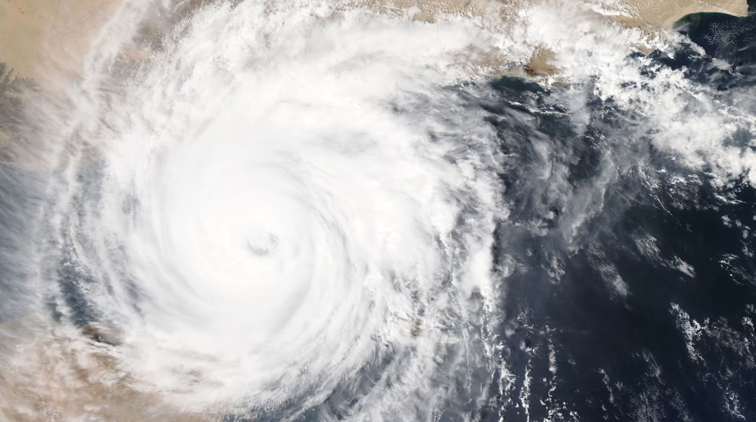 An aerial image of a typhoon moving across a country. The typhoon is made up of a spinning white cloud.
