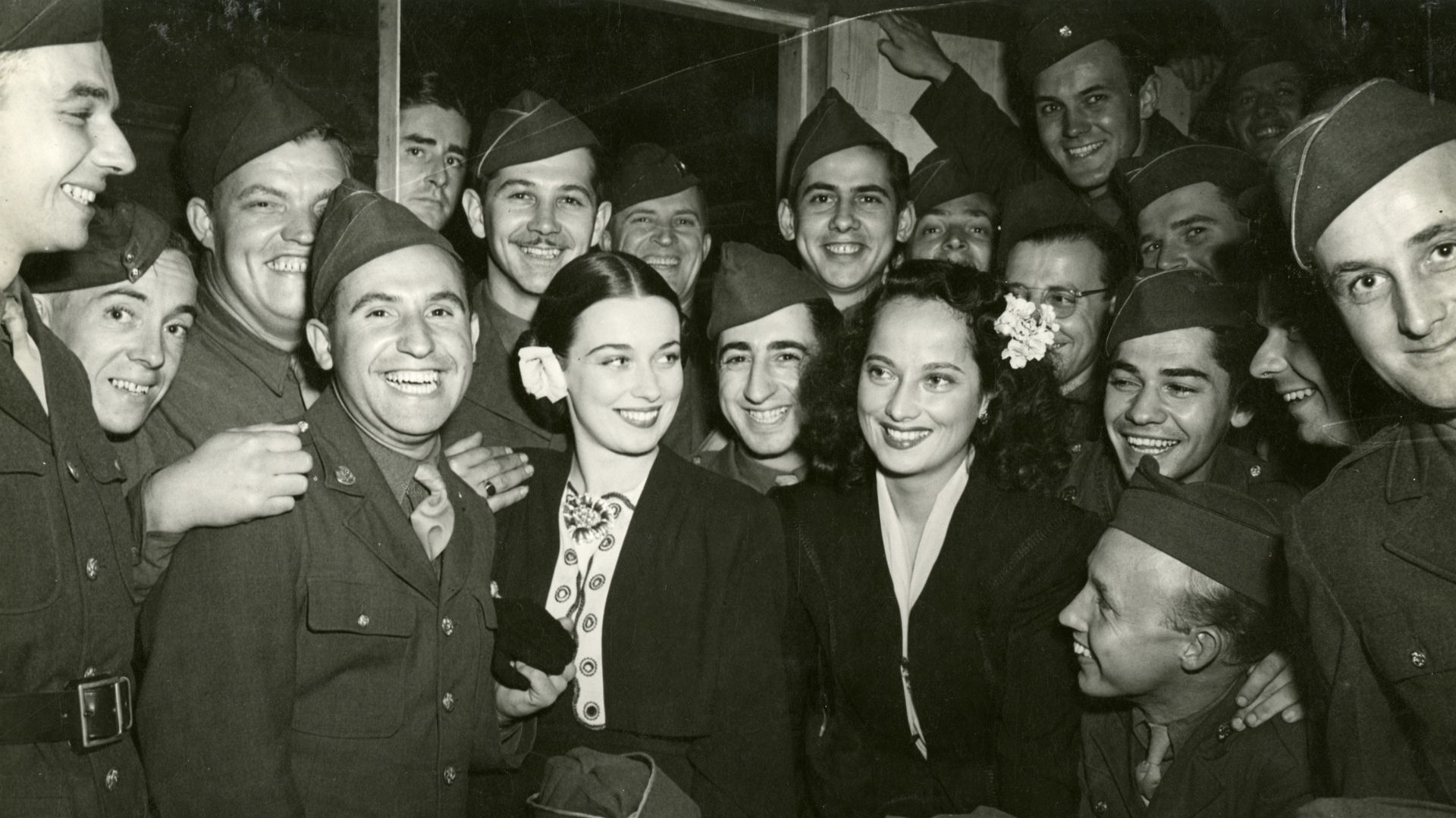 Actresses Patricia Morison and Merle Oberon posing with World War II soldiers.