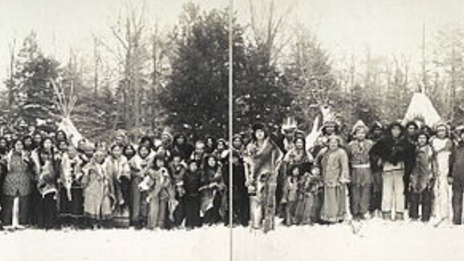 This is a black-and-white photo of an Iroquois tribe standing in front of some trees.