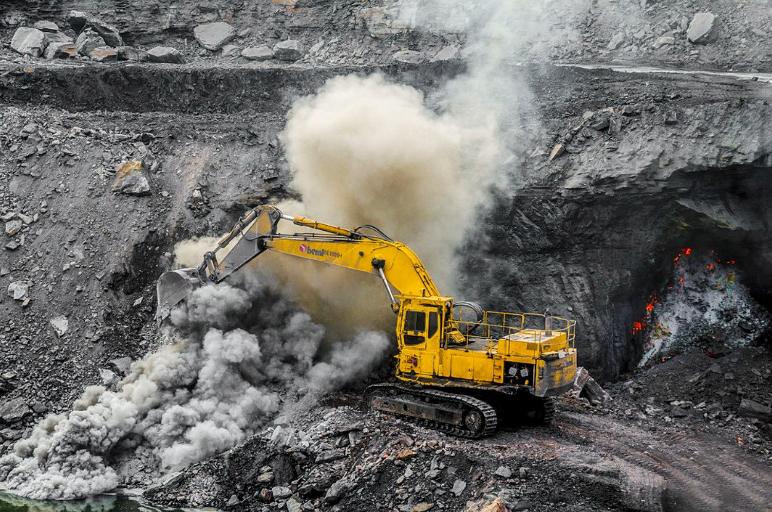 A large yellow digger is pictured in the middle of the Dhanbad mine complex in India