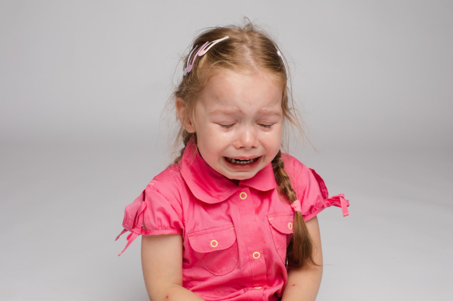 An image of a young child in a pink shirt crying