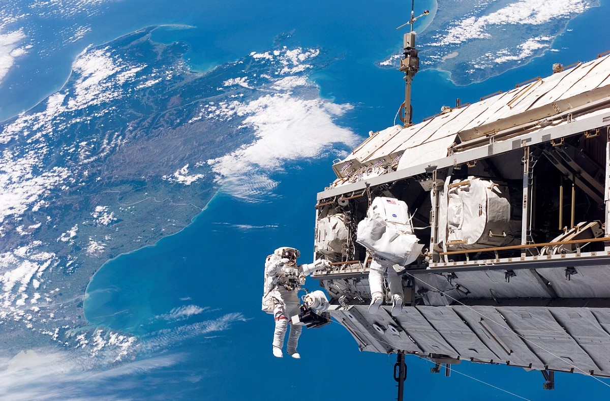 An image of several astronauts during a spacewalk above the nation of New Zealand
