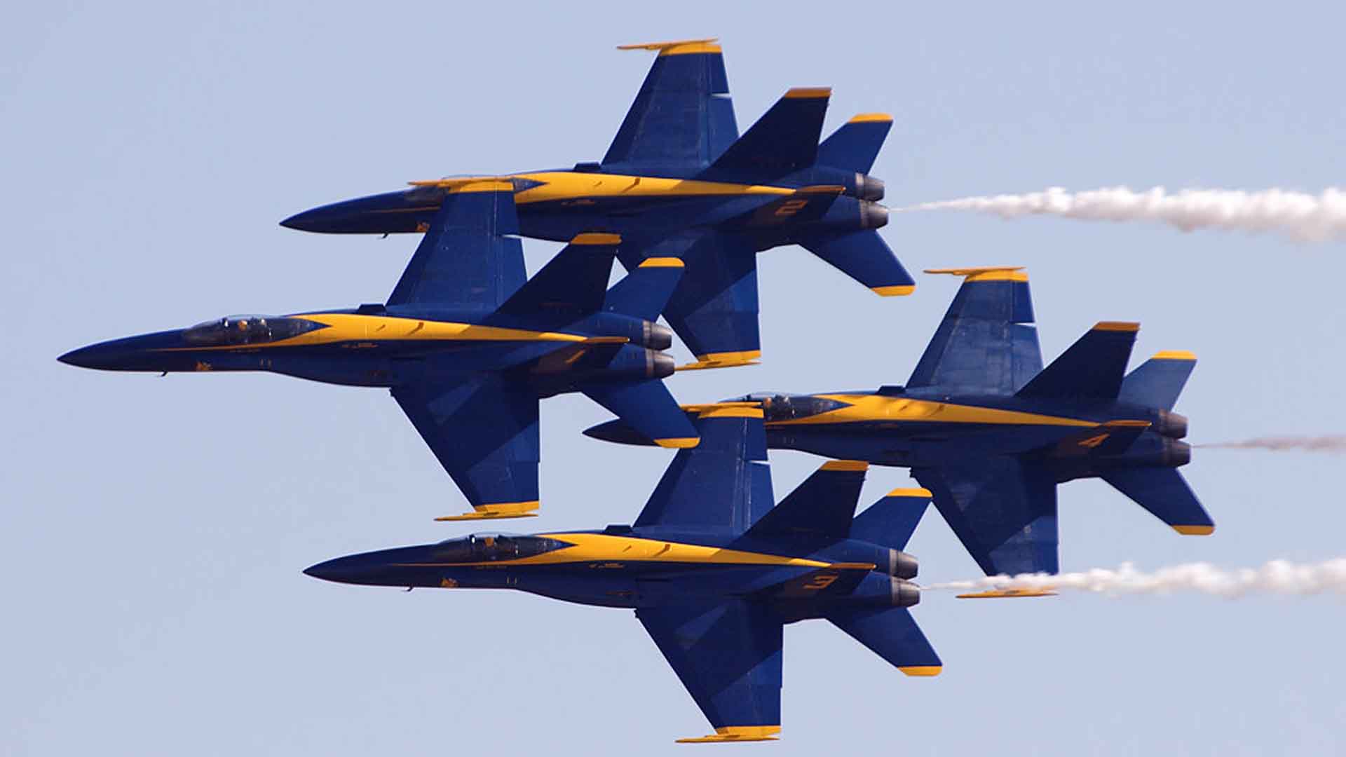 The Blue Angels F/A-18 Hornets "1–4" fly in a tight diamond formation, maintaining 18-inch (0.5 m) wingtip-to-canopy separation